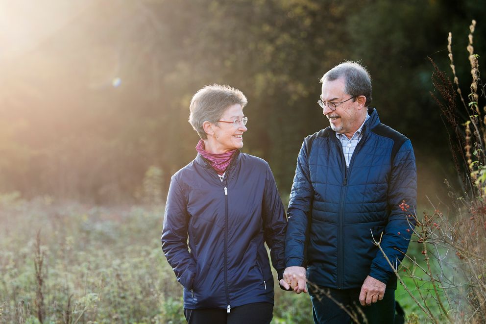 Eine Frau, selbst Apherese-Patientin, geht mit ihrem Ehemann im Grünen spazieren. Die beiden lächeln sich an.